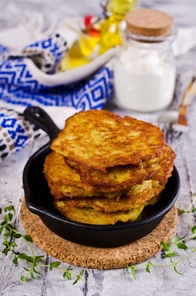 Boxty, an Irish potato pancake, sizzles in a skillet on a rustic wooden table.