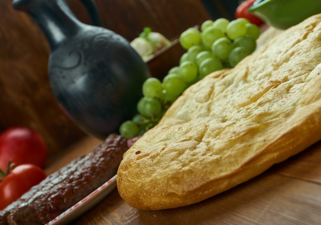 A pizza is sitting on a table next to grapes.