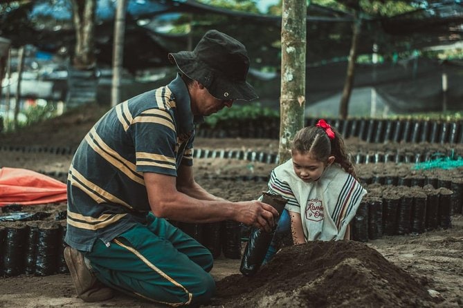 A man and a girl planting trees in the dirt while enjoying armenian food.