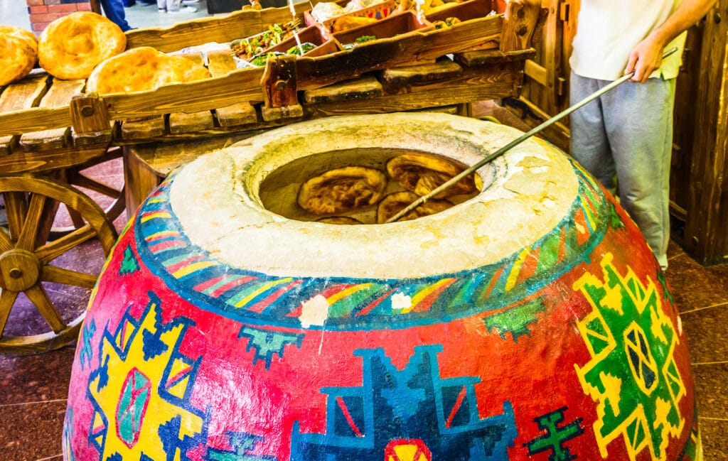 A man is standing next to a large pot of armenian food.