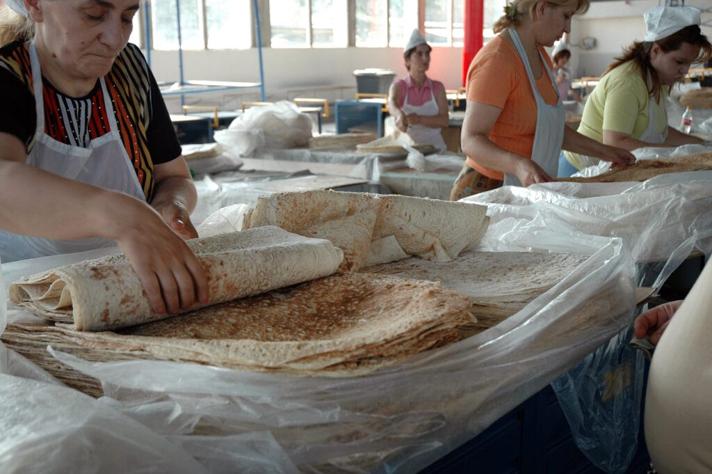A woman wearing an apron, diligently preparing delicious Armenian food.