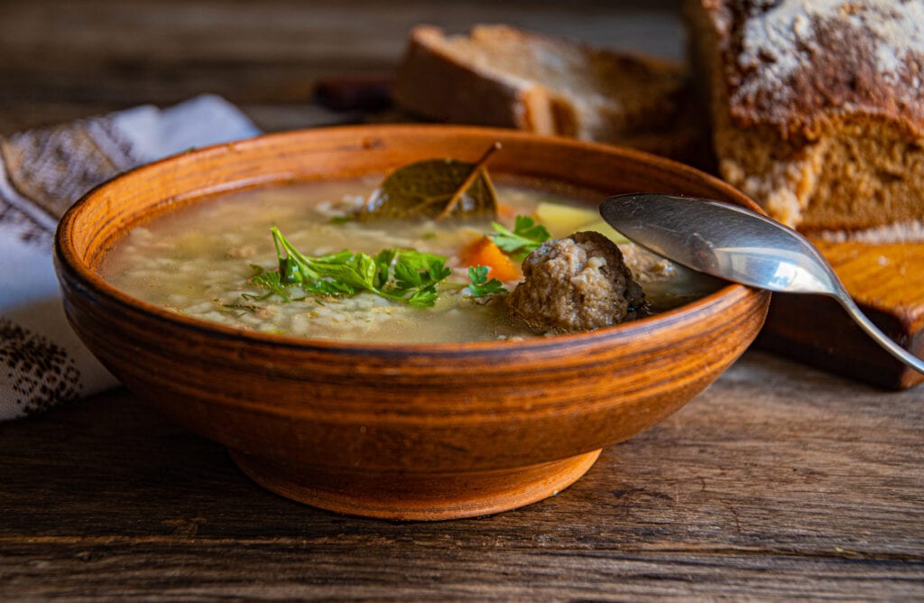 Armenian soup with meat and vegetables in a bowl on a wooden table.