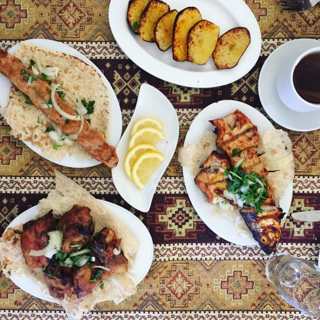 Four plates of Armenian food on a table with a cup of coffee.