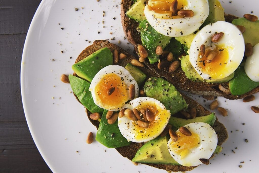 Avocado sliced on toast and topped with soft boiled eggs and pine nuts best breakfast in the world