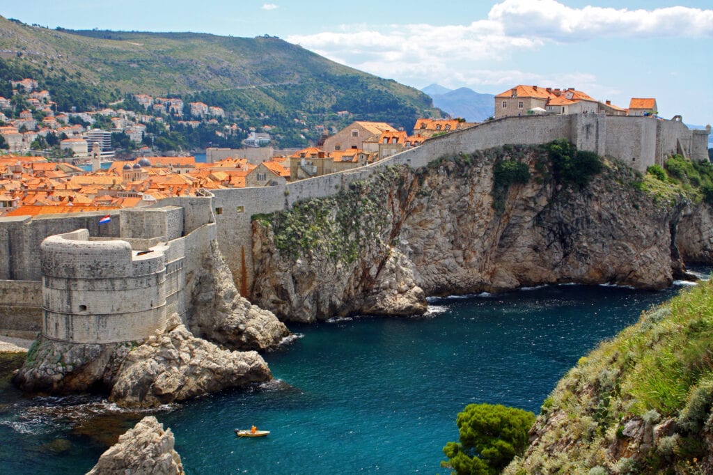 Croatia itinerary a view of Dubrovnik and the ancient old town white houses with terracotta roof scaling the cliffs above the sea