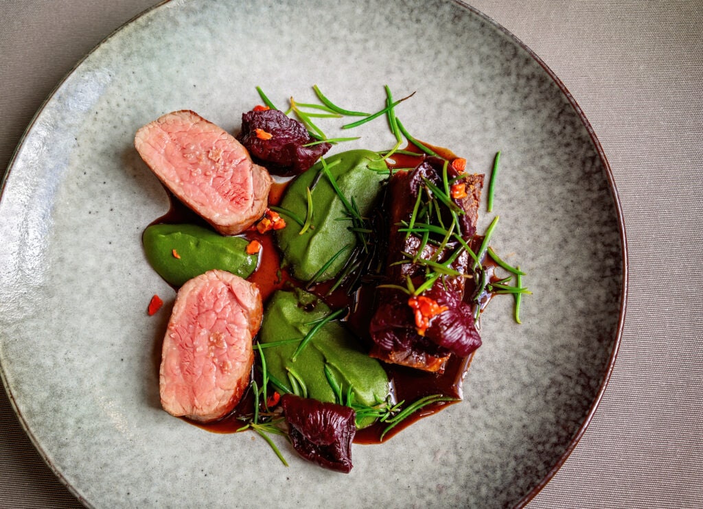 Bush food plate of grass fed beef, warrigal greens, sea fern and pepperberry jus