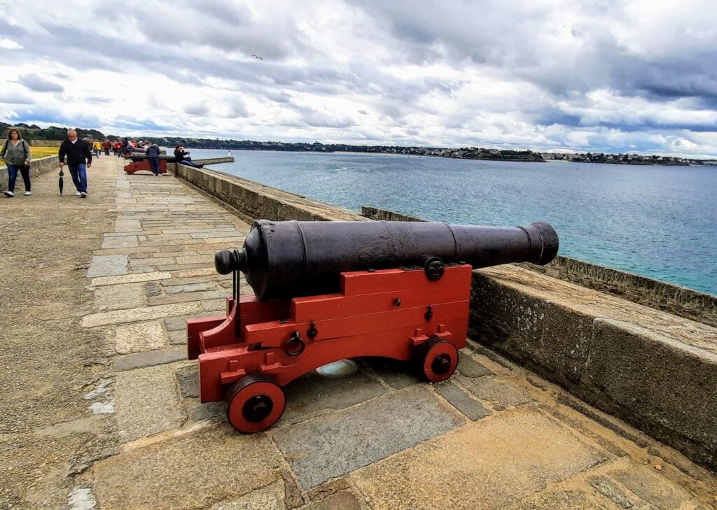 The ramparts of Saint Malo France looking out to sea with the ancient cannons pointed outwards and people walking the ramparts around the city