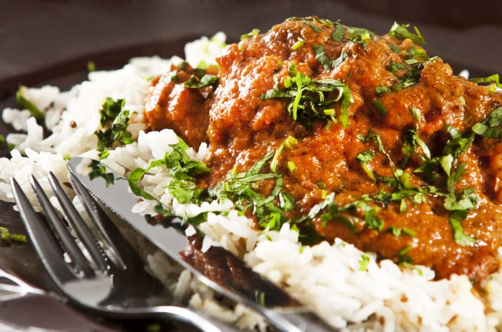 Chicken tikka masala served  with rice and garnished with cilantro leaves