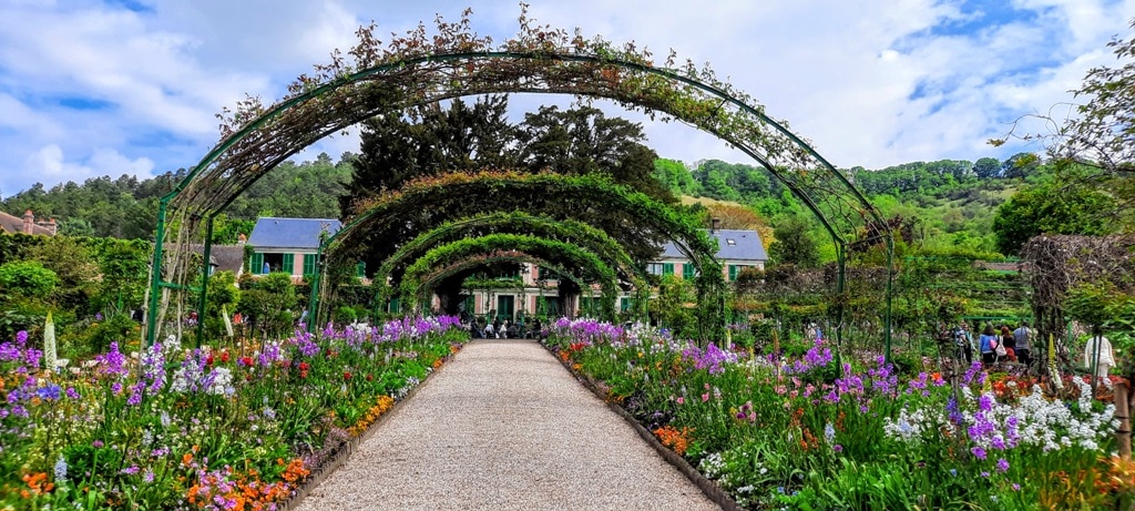 A series of iron bridges over the flower beds at Monet's garden in France. The flower beds are a riot of colour underneath the arches and beside each gravel walkway