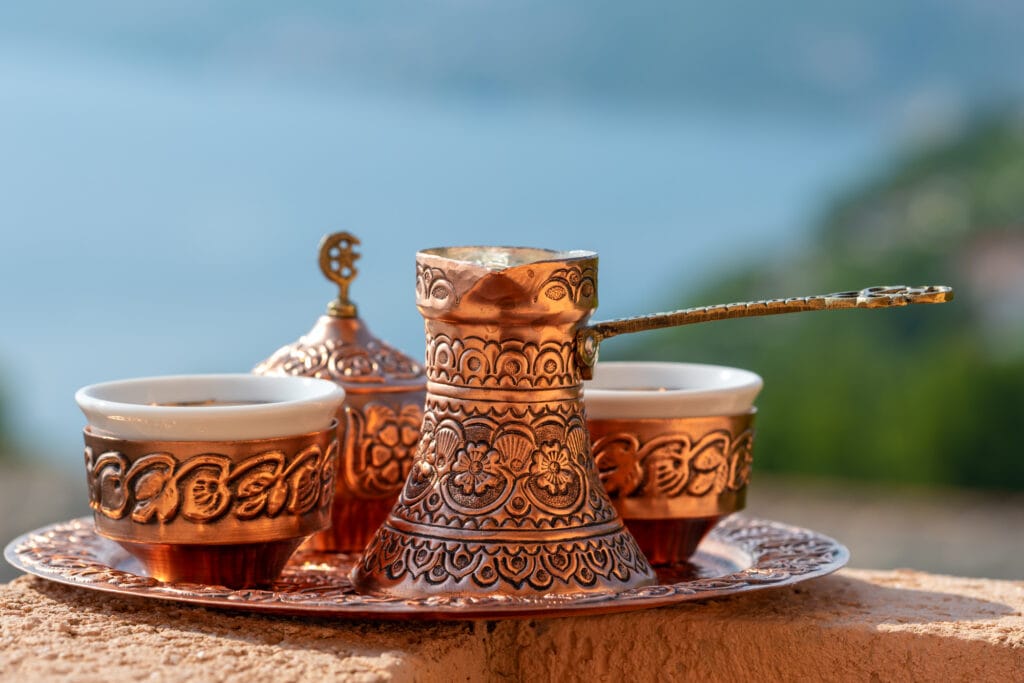 Traditional black bosnian coffee in beautiful copper cezve at wooden table. A complete Bosnian coffee set is called a kahveni takum