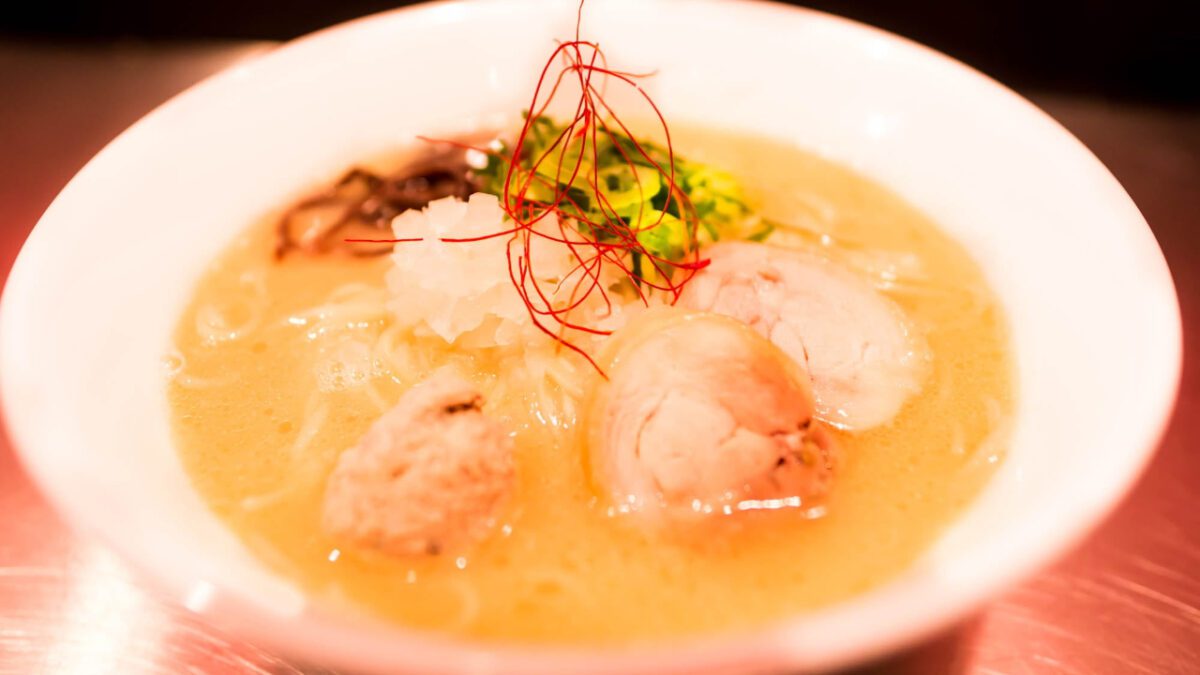 A white bowl filled with chicken soup and matza balls