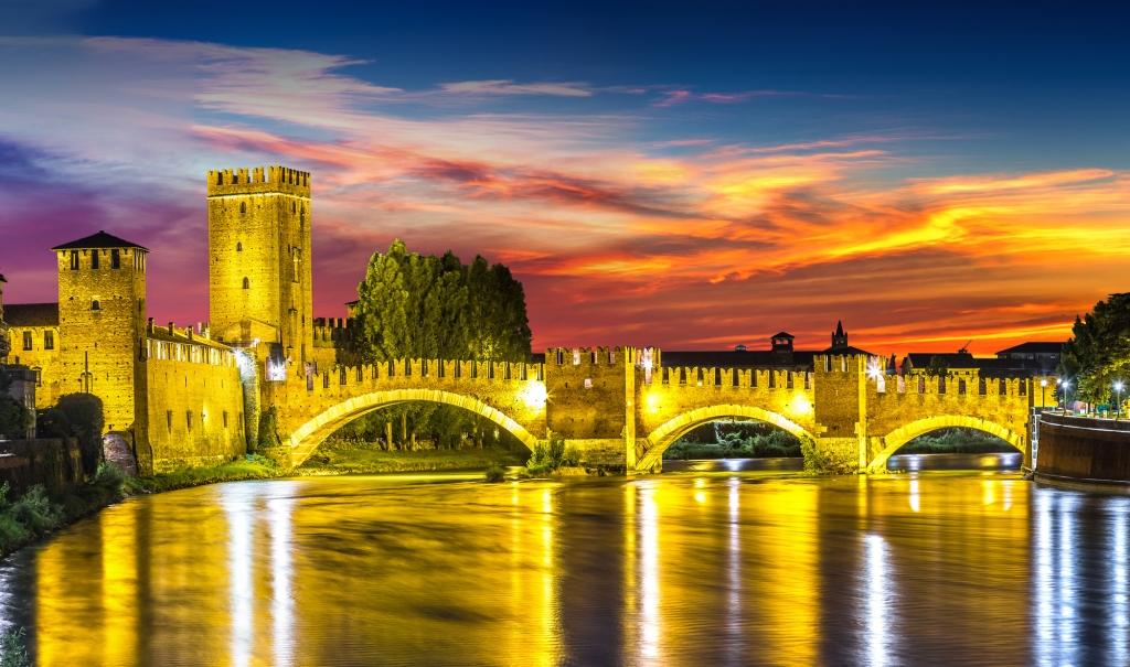Castle Vecchio at summer night in Verona, Italy a crenallated three arch bridge crosses the river in the golden light of sunset