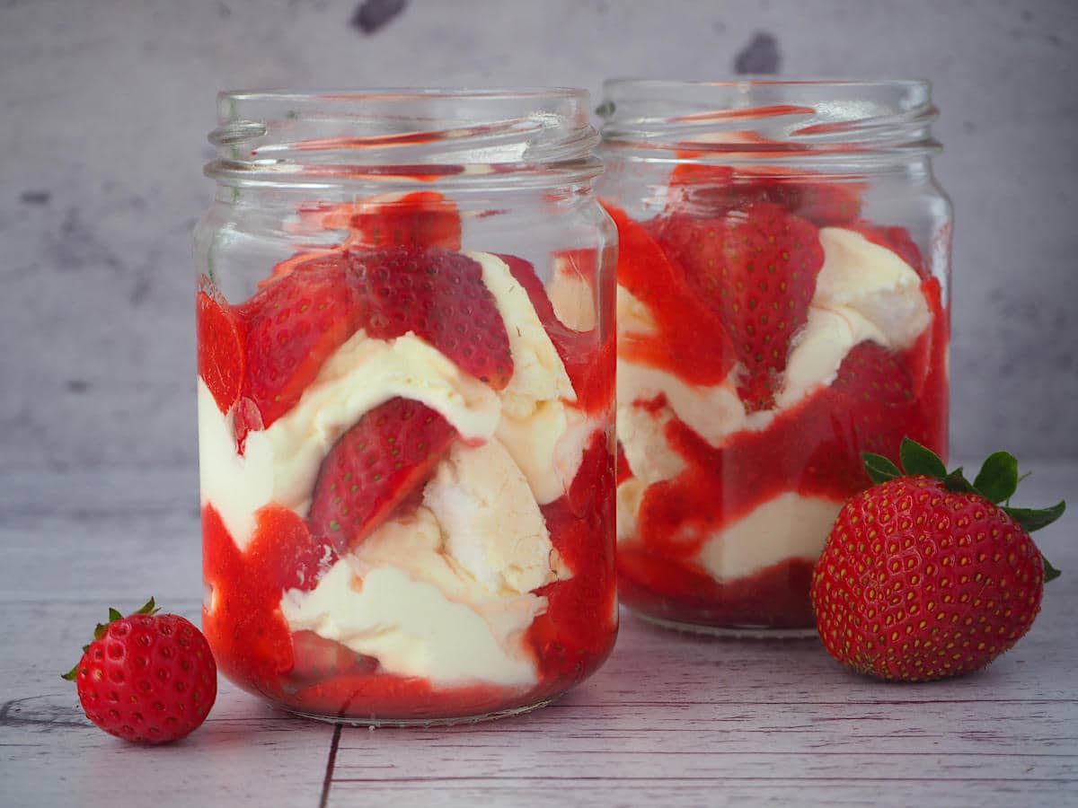 A traditional Eton mess served in a jam jar with layers of cream, crushed merinque and fresh strawberries