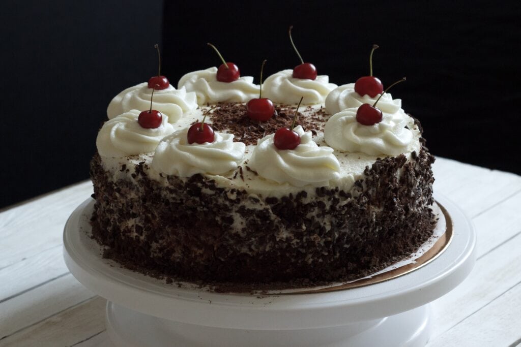 German Foods a black forest chocolate cake decorated with shaved chocolate, whipped cream and fresh cherries on top