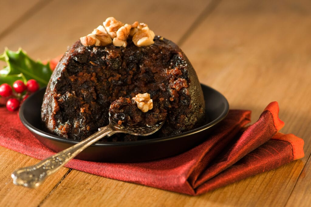 Spoonful of Christmas pudding decorated with walnuts in rustic setting