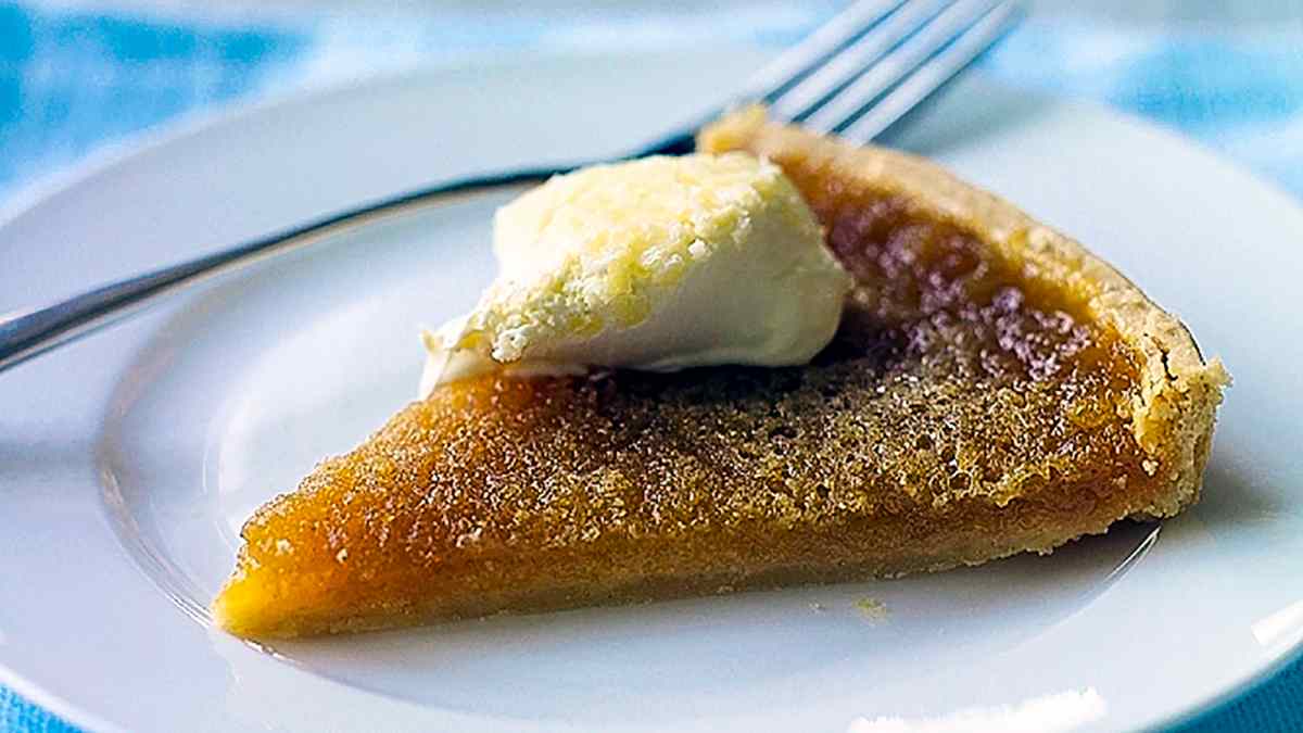 A slice of Treacle tart on a plate with a dollop of cream on top