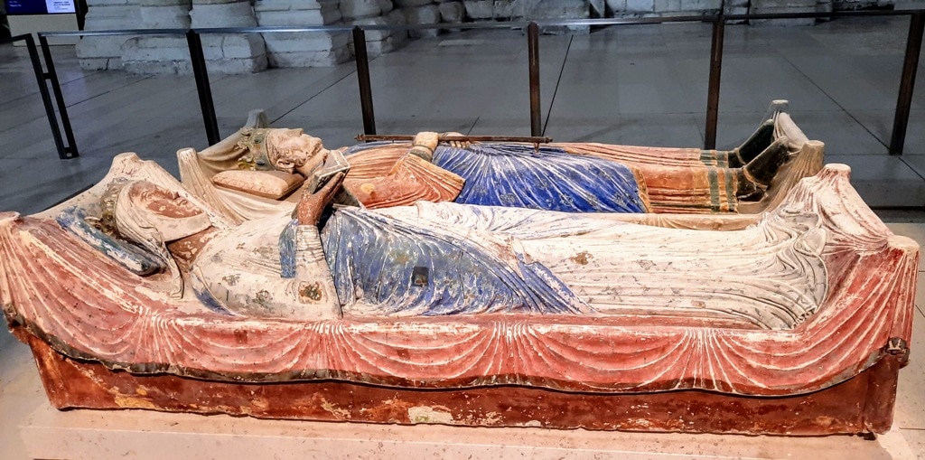 A statue of a woman laying on a bed in Fontevraud Royal Abbey museum.