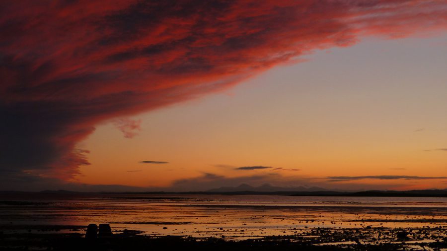 Greyabbey bay at sunset with the sky and huge clouds in a dark orange