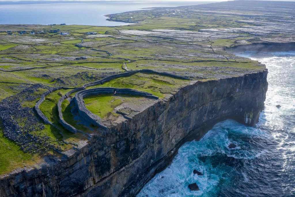Dun Aengus the large stone fort at the edge of the wild Atlantic way. with the sone walls pictured and the waves of the ocean below eating away the cliffs. 
