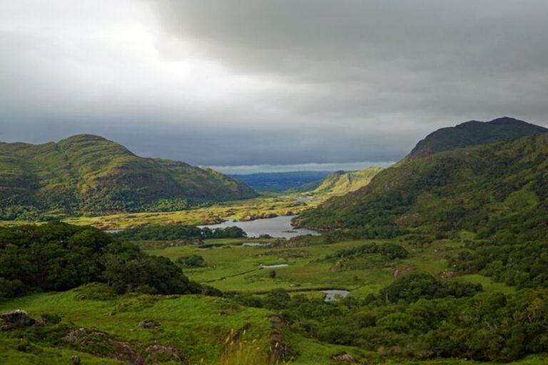 Ladies View Killarney stretches out in green hills with blue lakes interspersed among the hills.