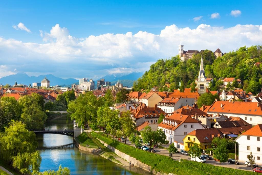 Things to do in Slovenia a birdseye view of Ljubljana with red roof tops,and the river flowing by this medieval looking city