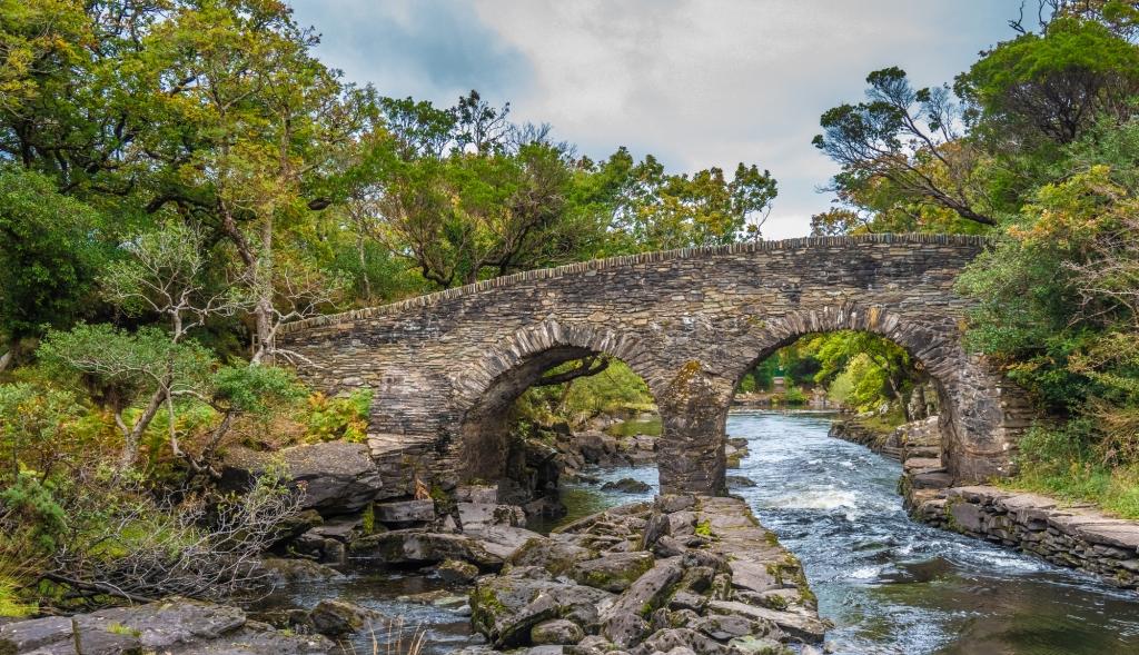 Best time to visit Scotland and Ireland. Old Weir Bridge, Meeting of the Waters, where the three Killarney lakes (Upper, Muckross and Lough Lane) meet Killarney National Park, County Kerry, Ireland.