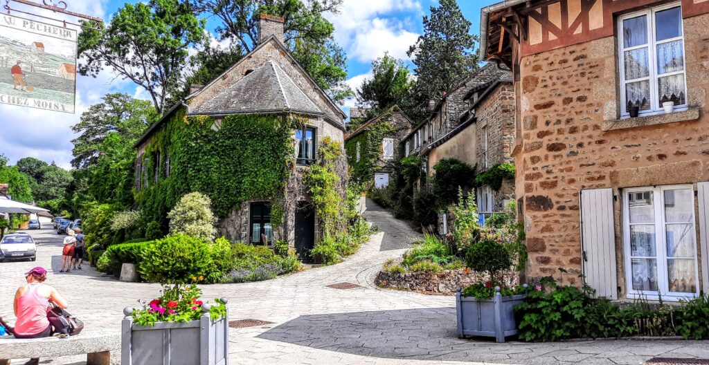 Saint-Céneri-le-Gérei plus beaux villages – beautiful villages of France. Stone houses with ivy and flowers climb the walls.