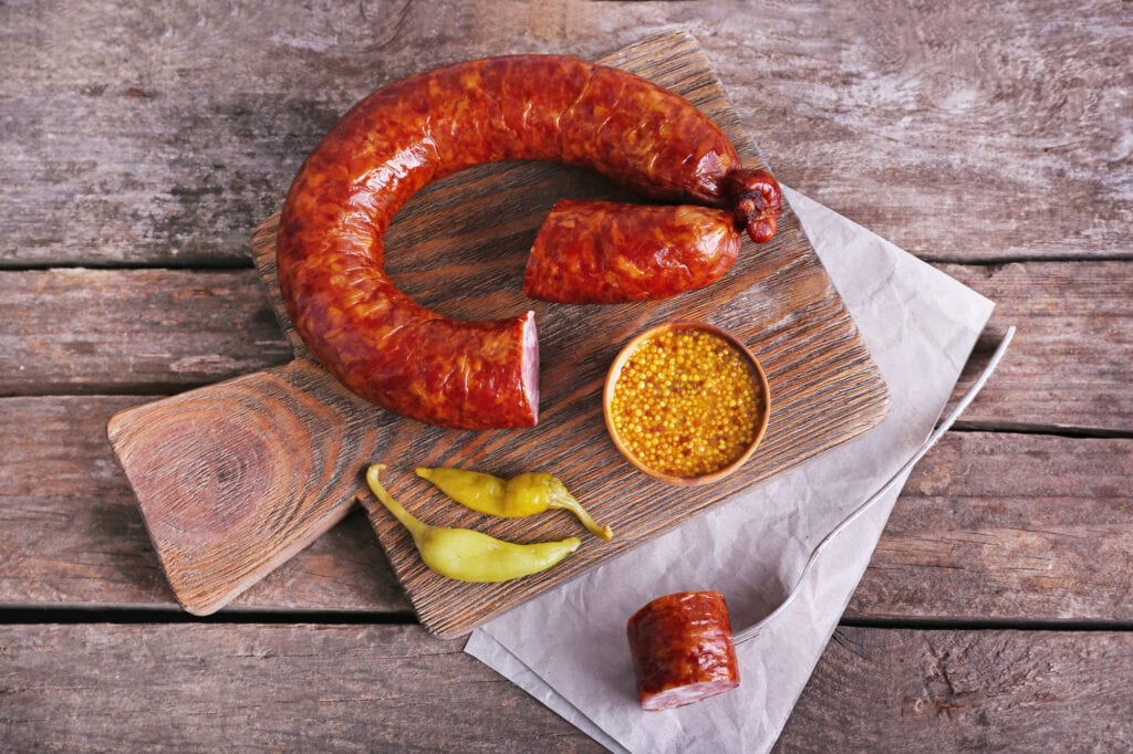 Smoked sausage on cutting board on wooden table background