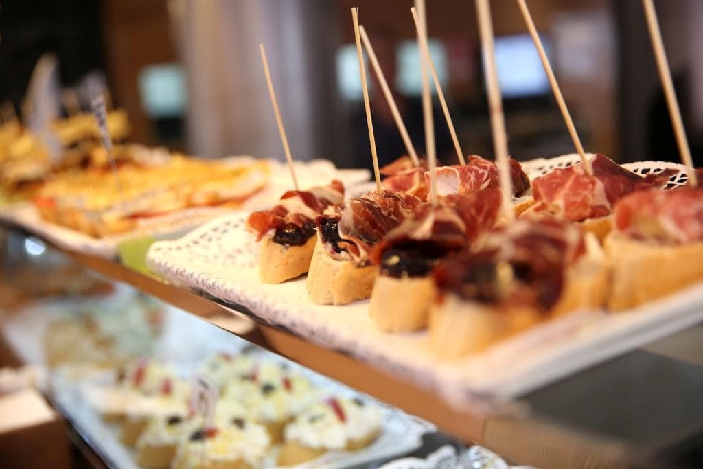 Closeup of Spanish tapas with small slices of crusty bread and meats skewered with large toothpicks