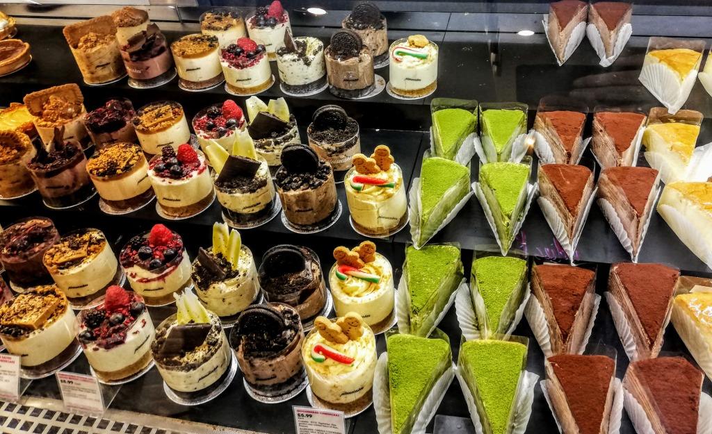 A range of French Christmas desserts, cakes and pastries in a glass cabinet, A variety of round glass cups filled with mousse and cream an various fruits