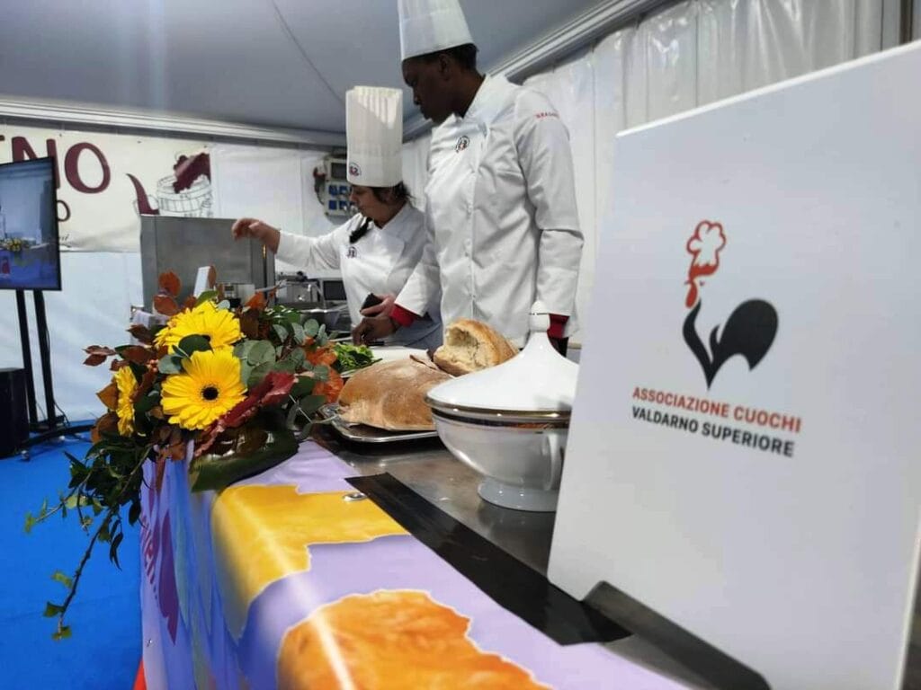 A Cooking class in Tuscany being filmed for a TV show, two chefs in white jackets are preparing fresh pasts