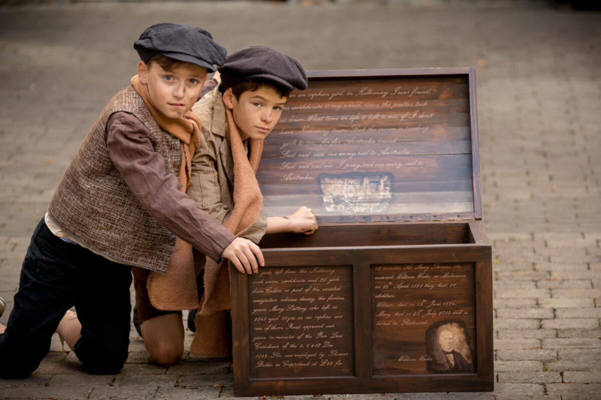 Two small boys are looking into a trunk at the Famine Heritage Museum
