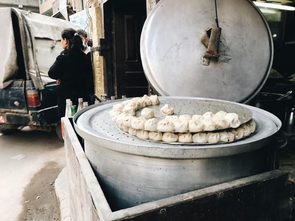 Momos are traditional steamed dumplings made of simple flour and water dough and filled with vegetables and sometimes meat. The most traditional meats used to fill momos are chicken, lamb, pork, and yak. Originally from the Himalayas, momos are comfort food that is eaten for lunch or dinner and served with aachar, a tomato-based dipping sauce.