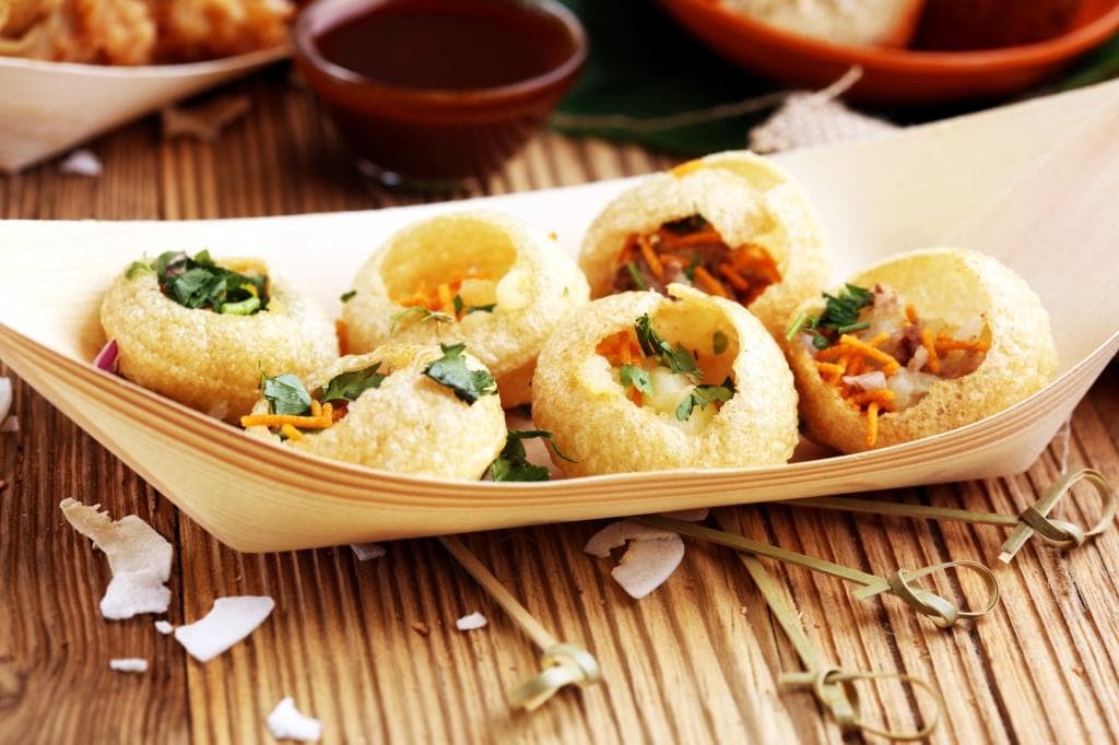 Pani puri which is potatoes, onions, chickpeas and chaat spice served in small hollow deep friend flour bowls