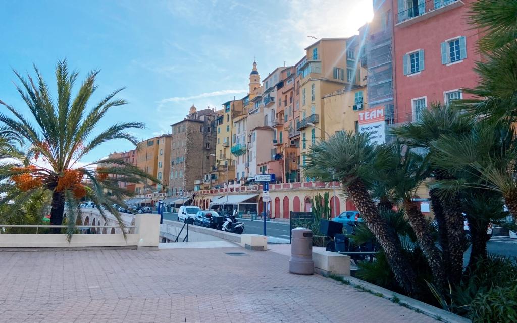 A street view of Menton France with palm trees and colourful buildings