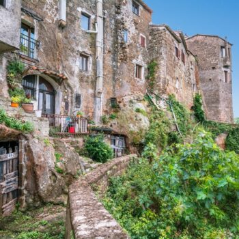 the medieval village of Calcata Italy off the beaten path Europe with stone buildings and steps decorated with flowers and greenery