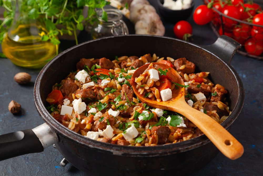 Traditional Greek cuisine. Lamb stew with feta cheese and vegetables. Dark background.