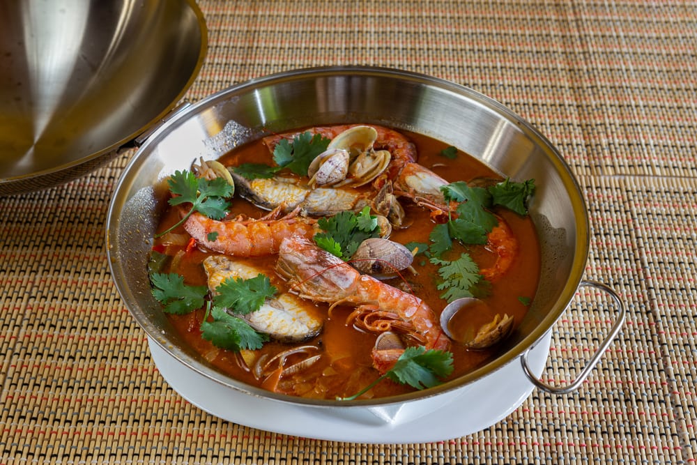 Traditional portuguese seafood dish cataplana. The main ingredients are sea shellfish, shrimp and green vegetables. Top view. 