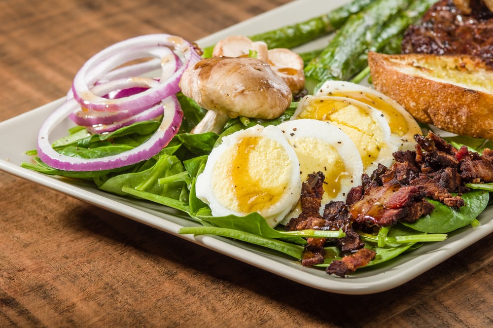 Steak and spinach salad with onion rings and mushrooms