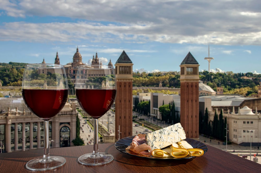 Two glasses of wine with meat and cheese snacks against Spain square in Barcelona, Spain the best wine tours in Europe