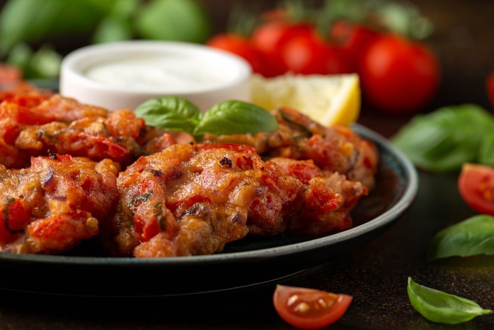 Greek tomato fritters, tomatokeftedes served with yogurt on plate.