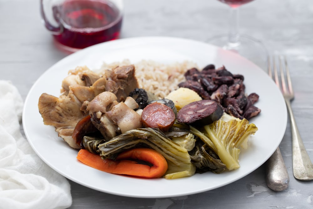 typical portuguese dish boiled meat, smoked sausages, vegetables and rice on white plate