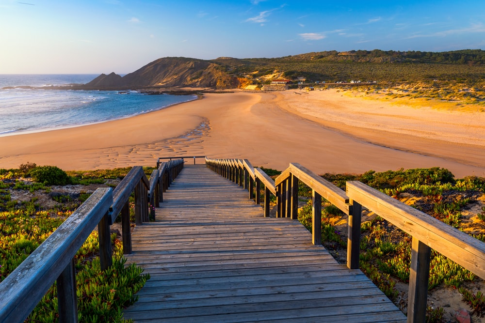 Wooden walkway to the beach Praia da Amoreira, District Aljezur, Algarve Portugal. Panorama from Amoreira beach in the Algarve Portugal. Beach and estuary of the Aljezur river, Praia da Amoreira.