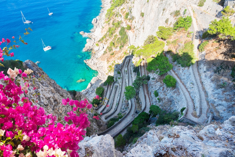 Via Krupp vintage stairs to sea, Capri island with flowers, Italy