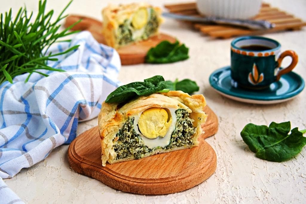 Portioned traditional Italian Easter cake or tart with spinach, ricotta and whole eggs. Italian food. Dishes Easter. Baking with greens.