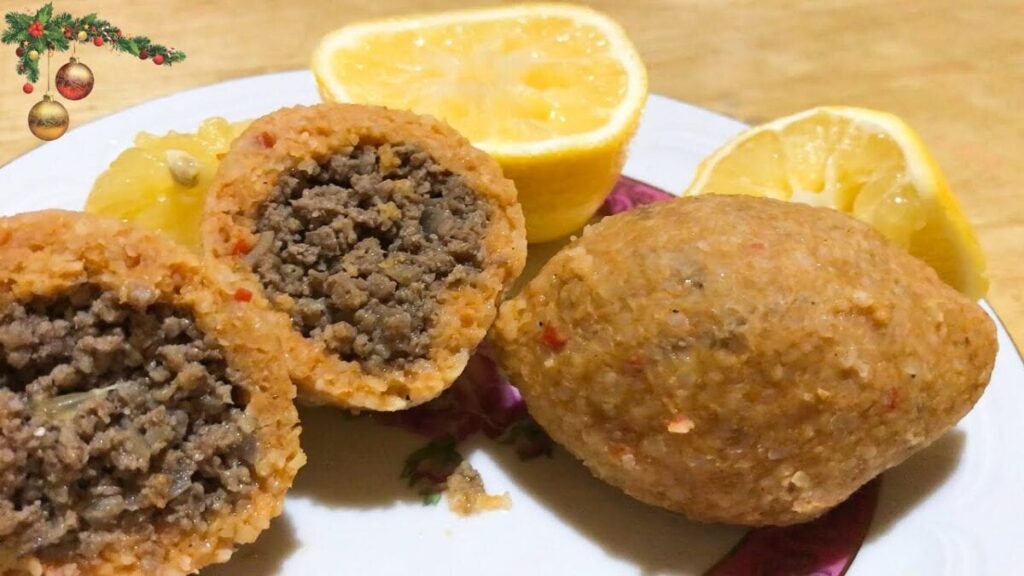 An Armenian plate with meatballs and lemon wedges on it.