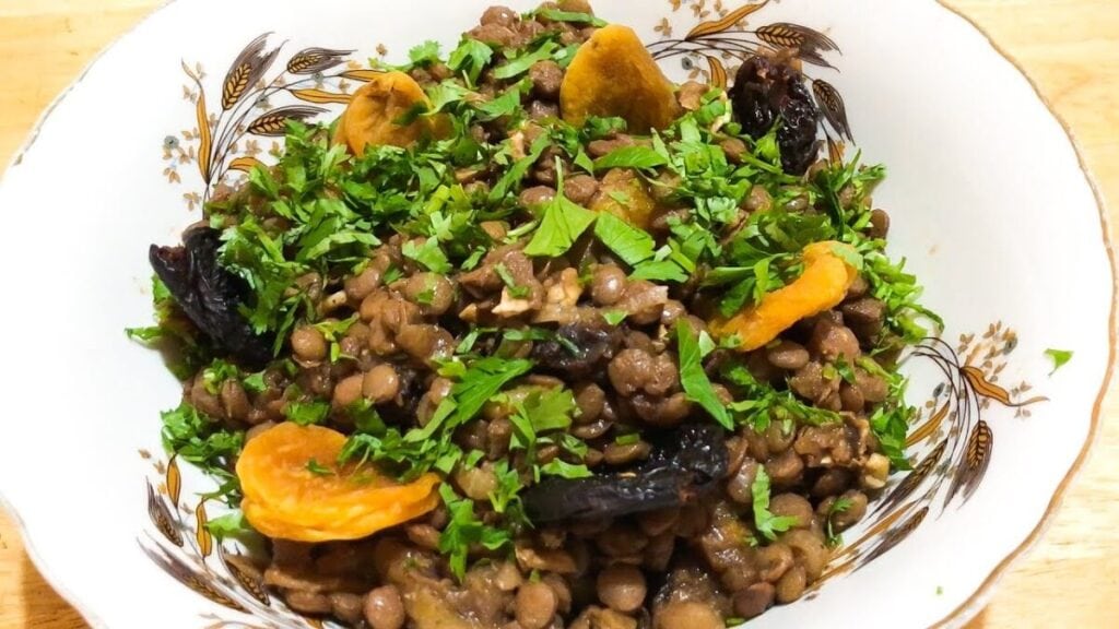 An Armenian bowl of lentils and oranges on a wooden table.