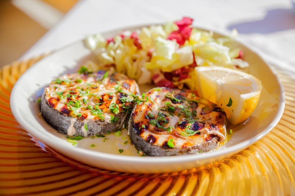 close-up two grilled swordfish steaks with lemon slice and cabbage