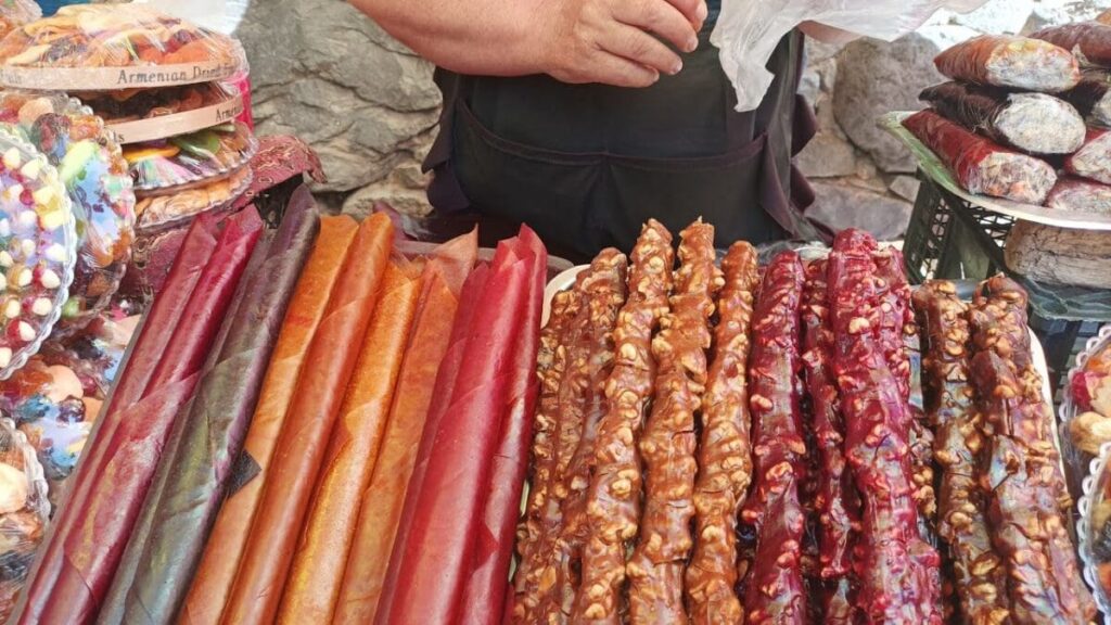 A man is standing in front of a display of different kinds of Armenian food.