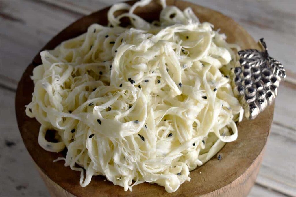 A bowl of shredded cheese with a spoon on top, perfect for indulging in Armenian cuisine.